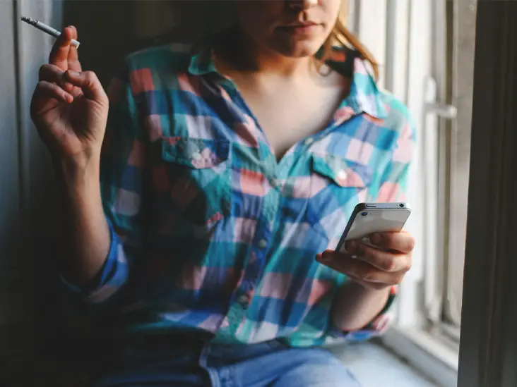 woman-home-smoking-cell-phone-window